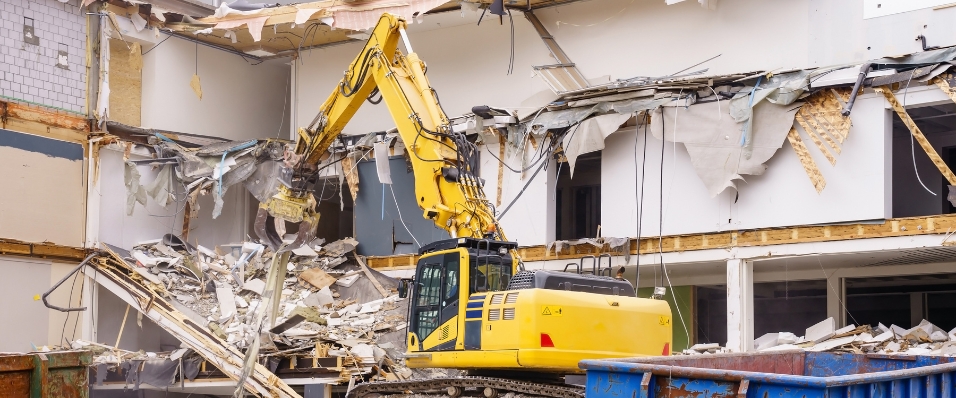 Excavator carrying out commercial demolition of a multi-story building.