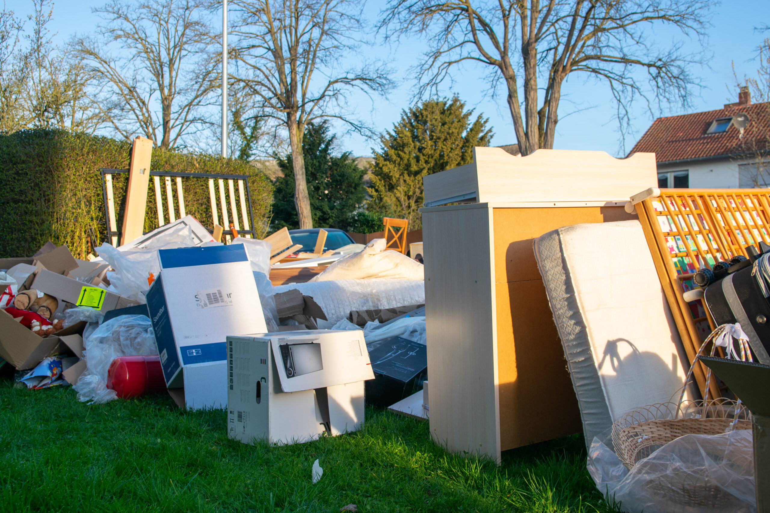 exterior-demo-section-01 Old furniture, boxes, and household junk piled on a front lawn during a residential junk removal cleanup.