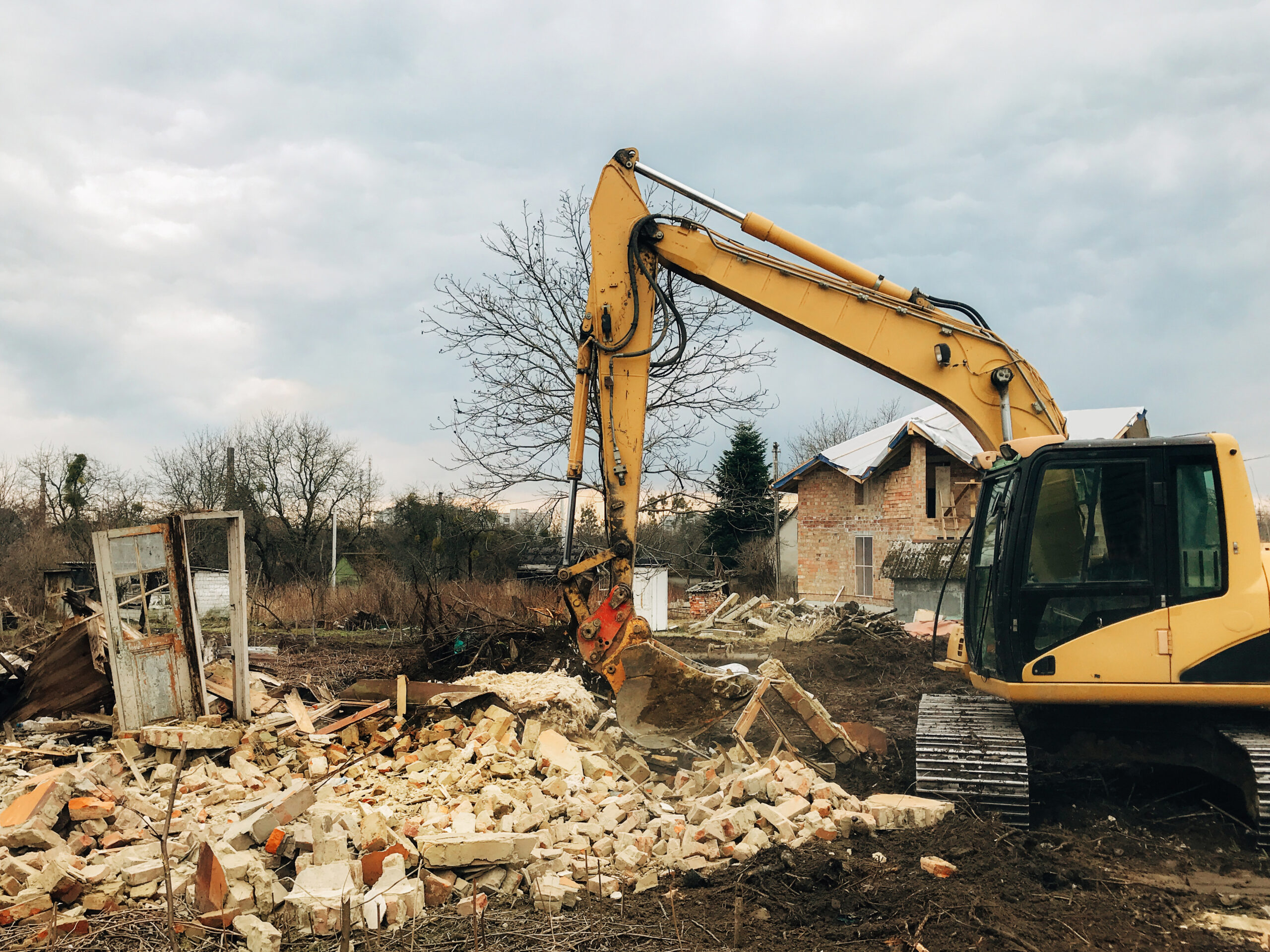 exterior-demo-section-01 Excavator clearing rubble during an exterior demolition of a residential building.